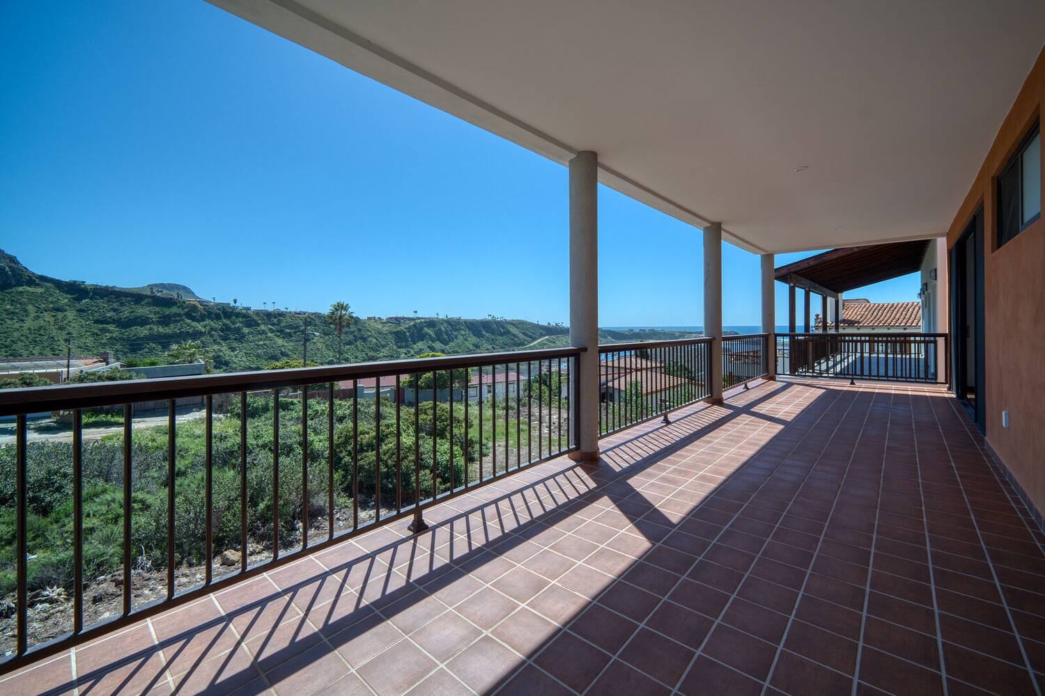 Covered main-floor terrace with columns, looking out to the hills and the ocean