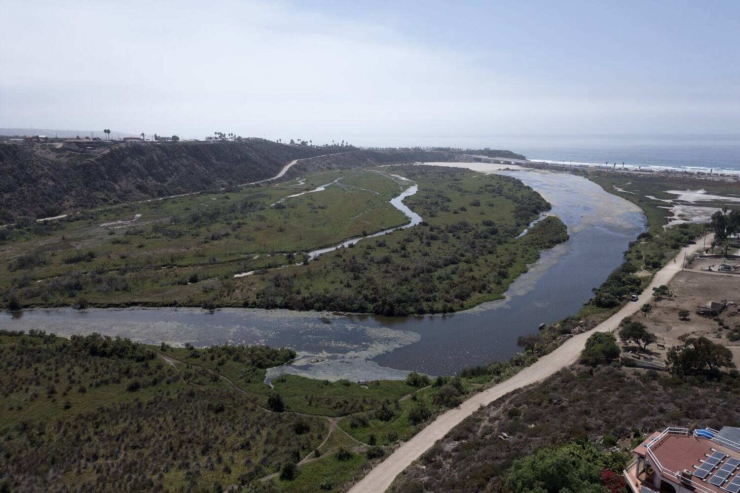 Aerial of the river estuary winding out to the Pacific below the house