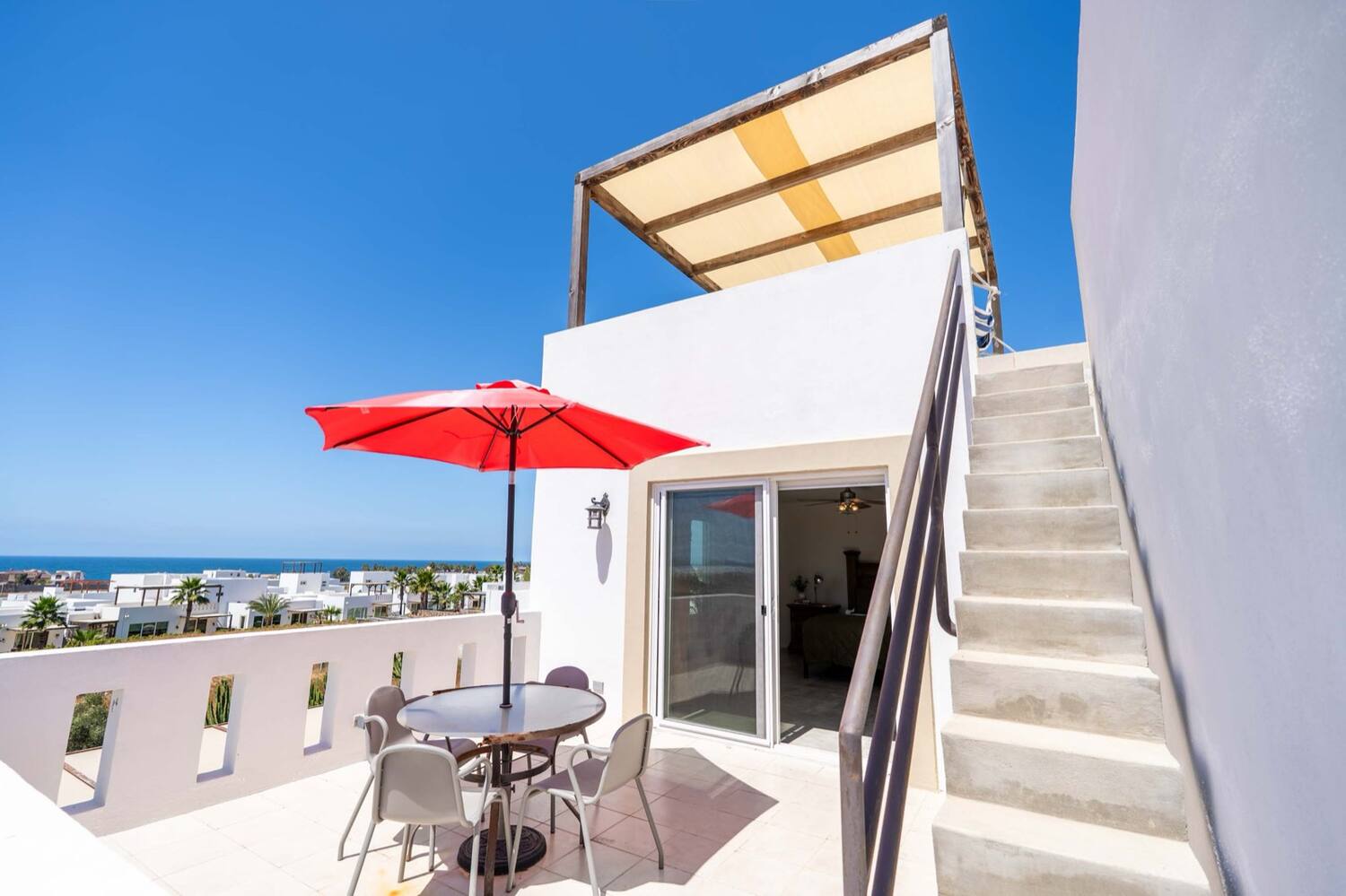 Upper deck with a shaded table and the ocean beyond