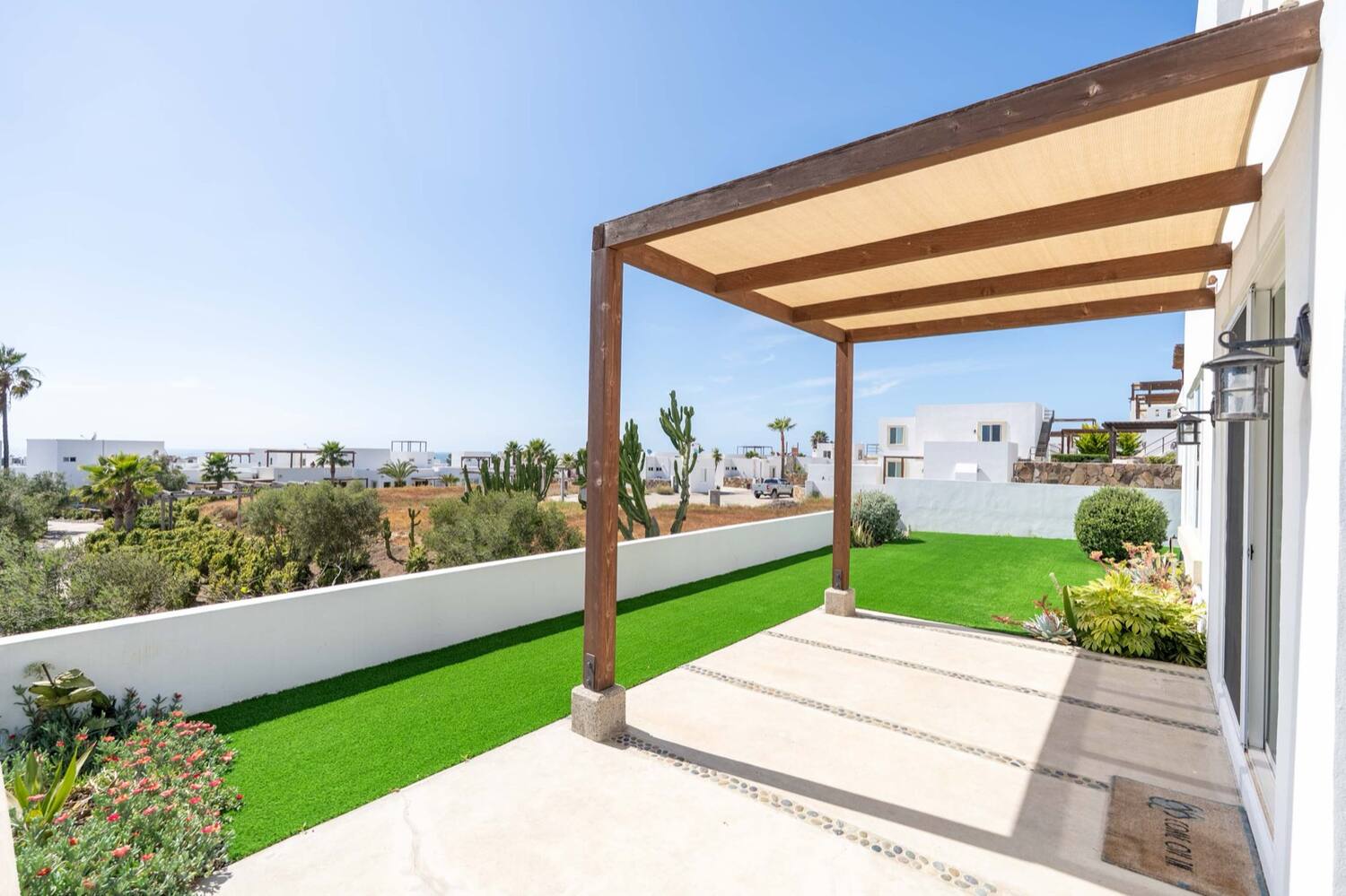 Covered porch with pergola beside the synthetic-grass backyard
